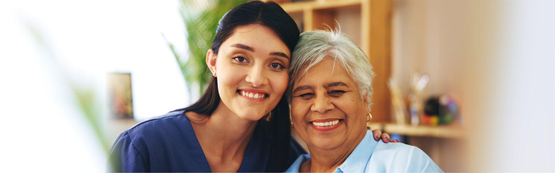 Two smiling women are posing indoors